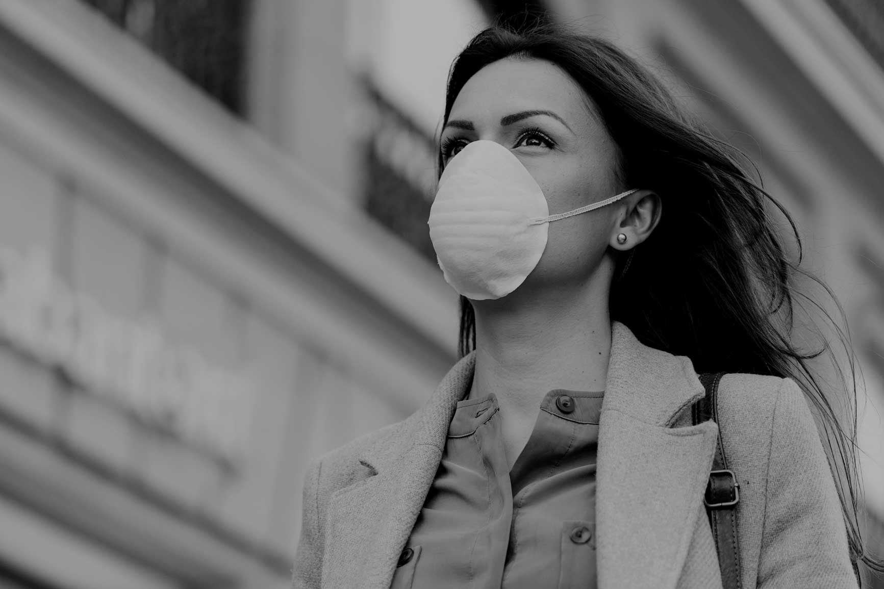Woman walking down street in businesswear wearing a mask